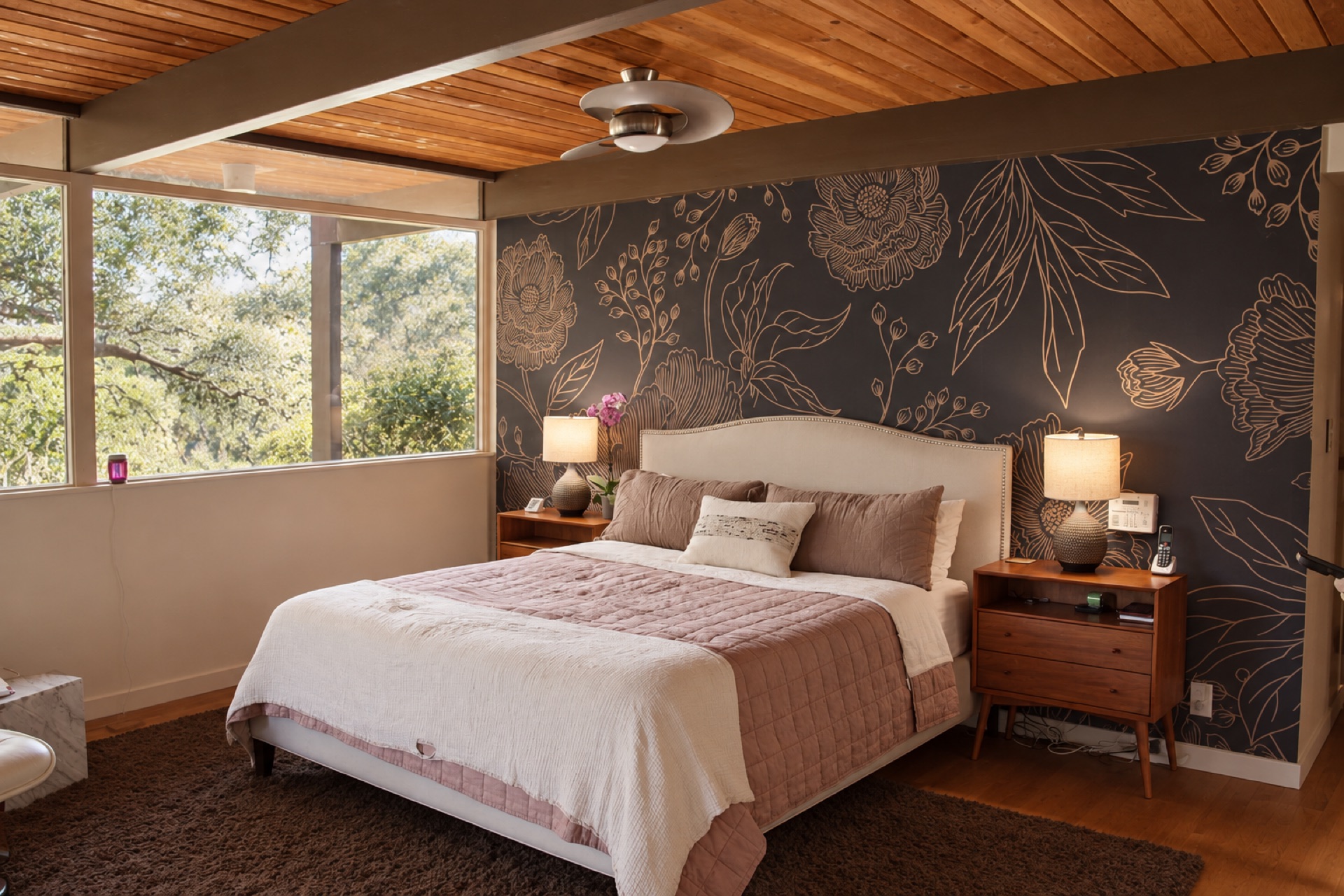 Bedroom with wood beam ceiling and floral accent wall in a mid-century modern home