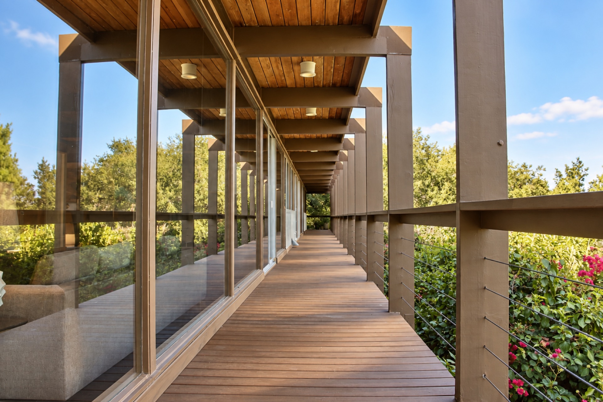 Covered wood deck walkway with glass railing at a mid-century modern home in Los Angeles